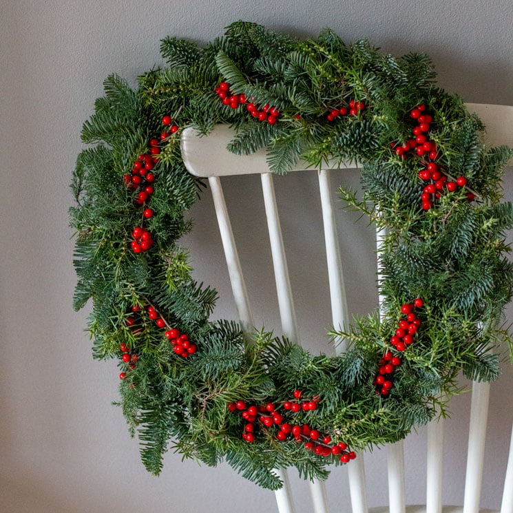 Julkrans med gröna barrkvistar och röda ilexbär.