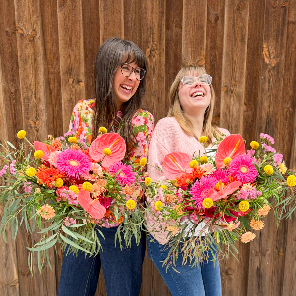 Två florister från Interflora Limhamn visar sina ståtliga vinnarbuketter i rosa, aprikos och gult