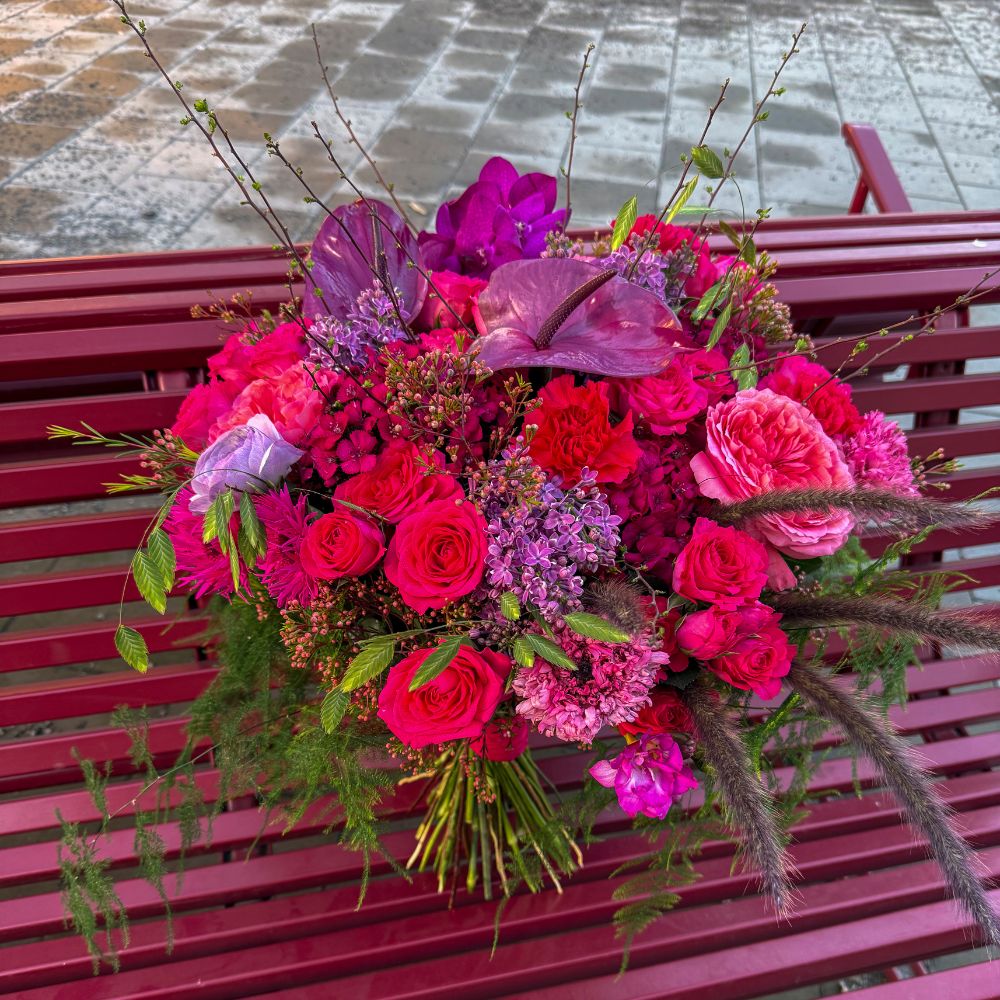 Vinnarbuketten ovanifrån på en rosa bänk, med rosor, gerbera och krysantemum i rosa och lila toner