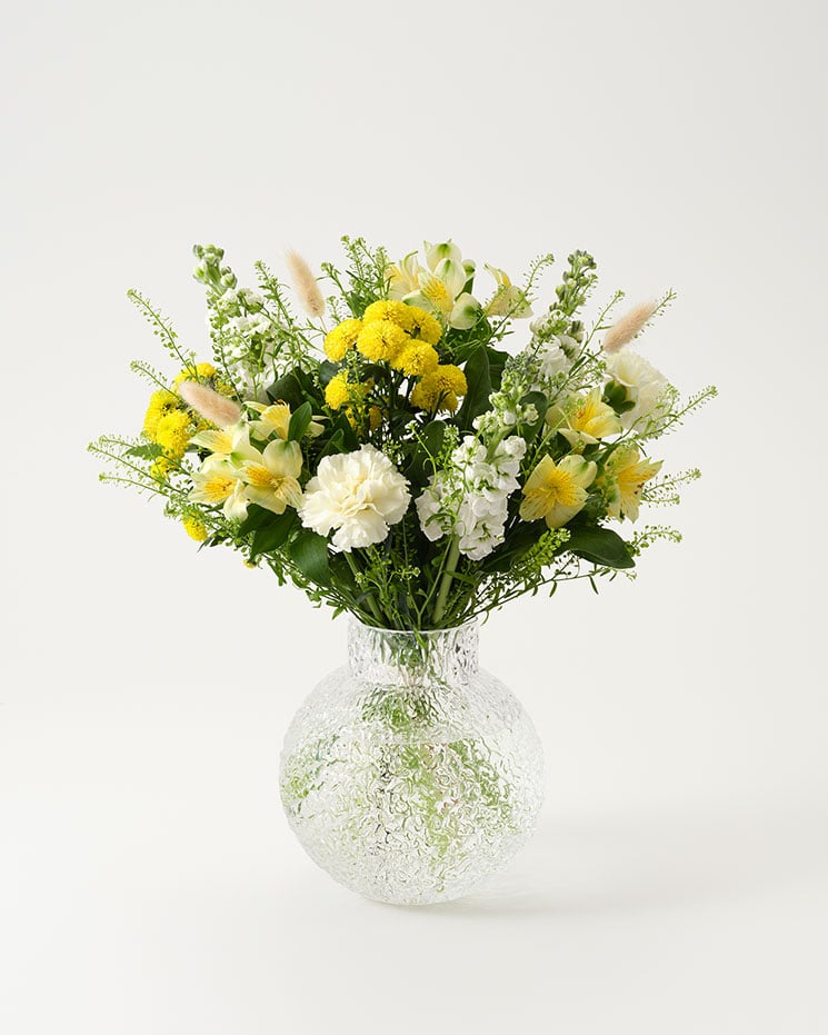 "Solglimt", en ljuvlig bukett i olika gula nyanser tillsammans med vita inslag. En kombination av vit lövkoja, gul alstroemeria, santini, gul nejlika, torkad lagurus och grönt. 