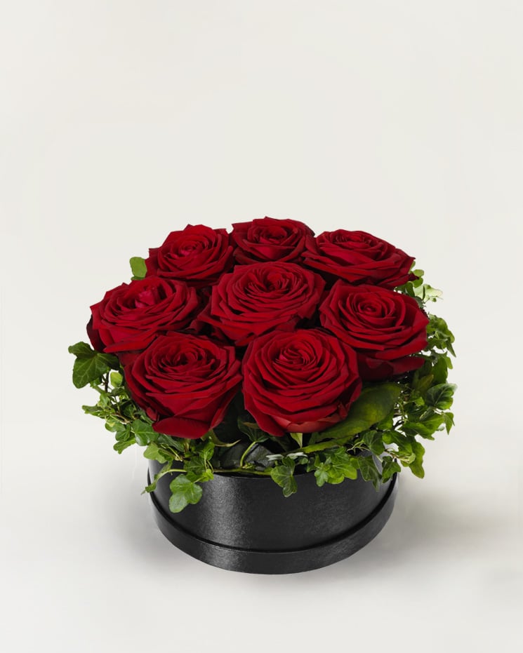 Rund hattask (ca 18 cm i diameter), fylld med röda rosor och dekorationsgrön. Finns att beställa hos Interflora.