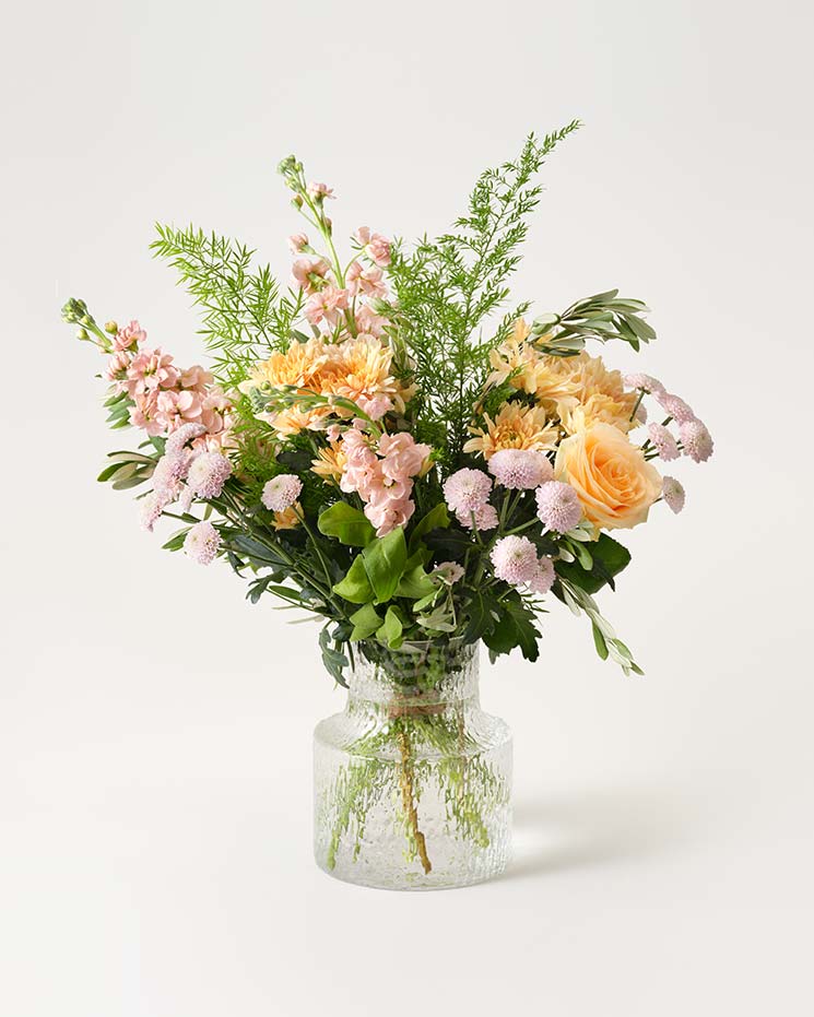 Vacker bukett i rosa, orange och grönt, med lövkoja, santini, krysantemum. Välj mellan fyra storlekar - de två största innehåller även aprikosa rosor.